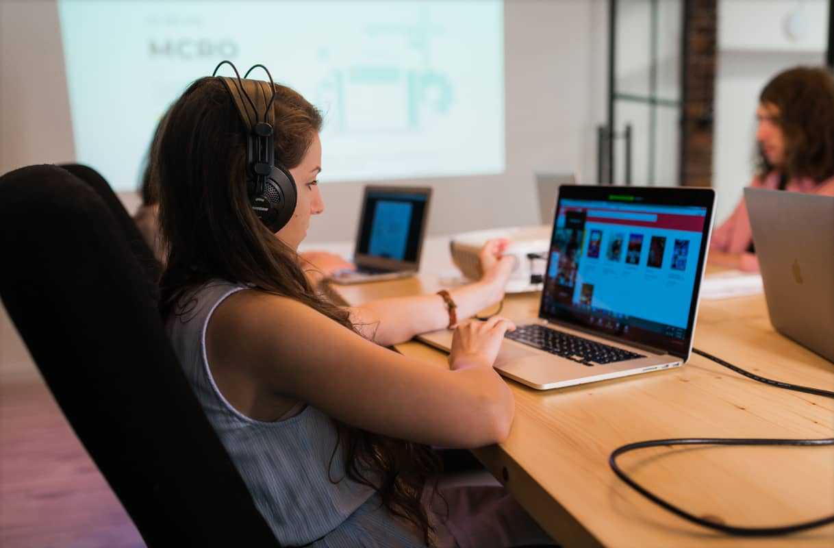 Closeup of a woman with headphones on working on a laptop
