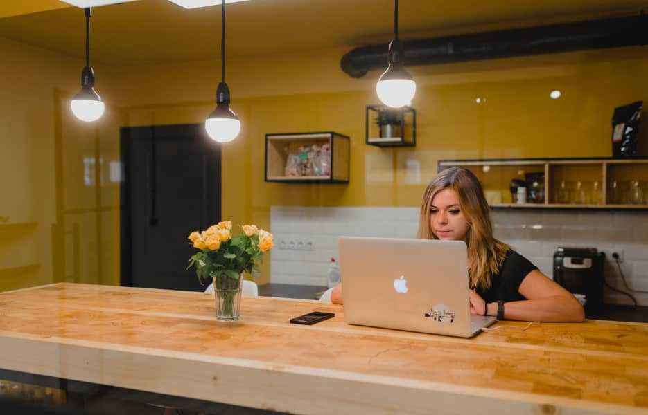 Woman working on a laptop in an office with yellow walls